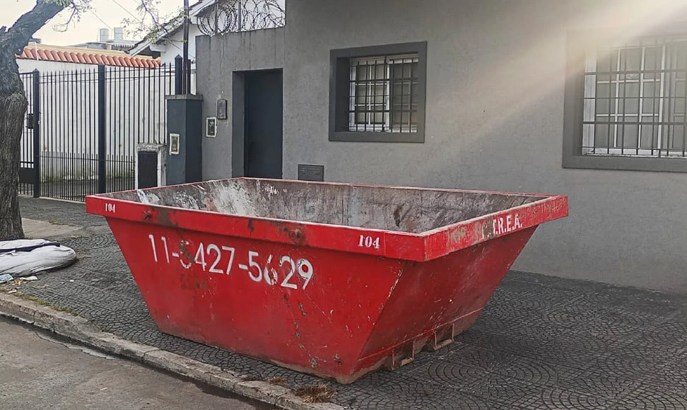 Volquete de alquiler colocado en la puerta de una casa para escombros y residuos